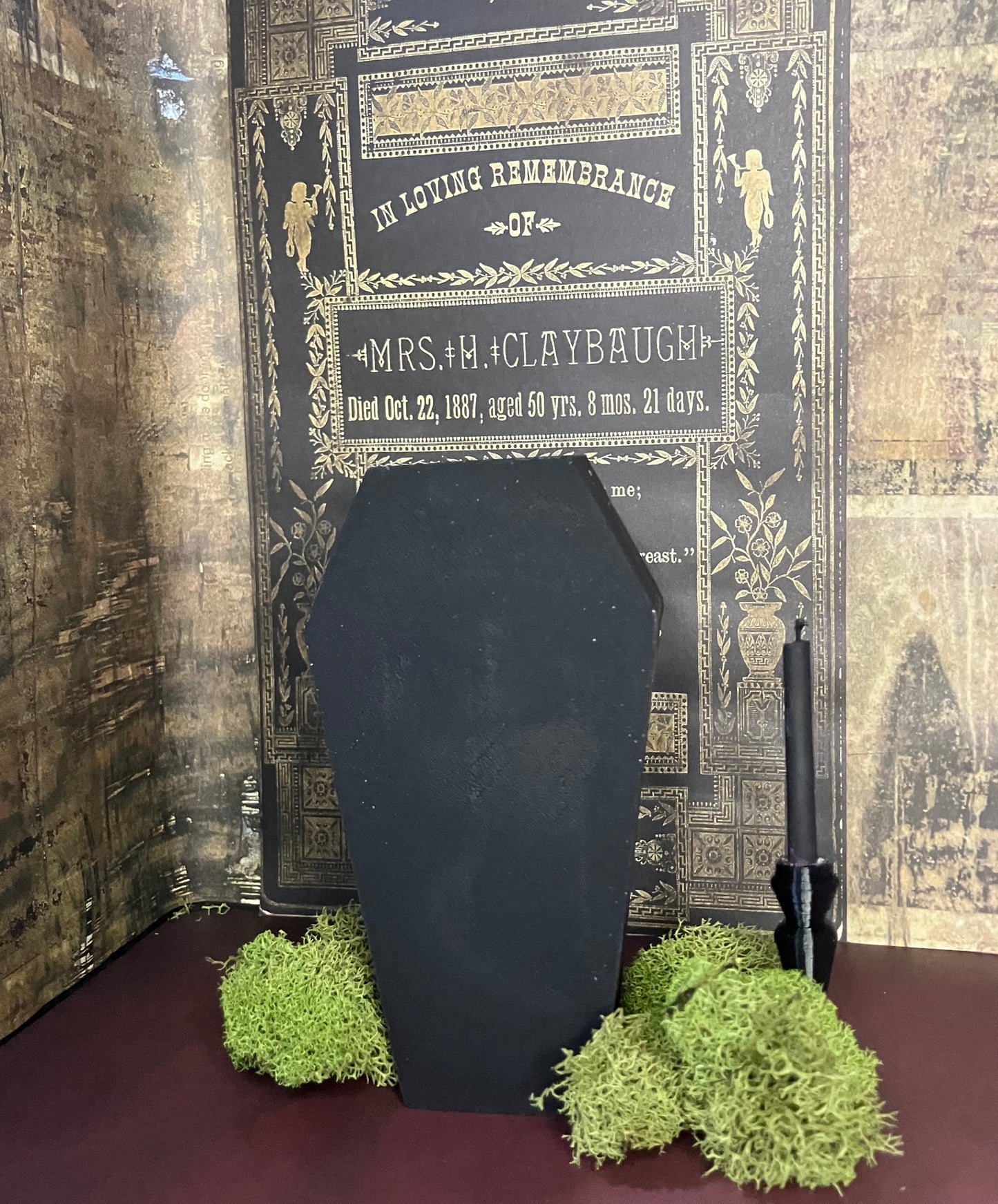 Black coffin soap with green moss on a dark background with decorative text