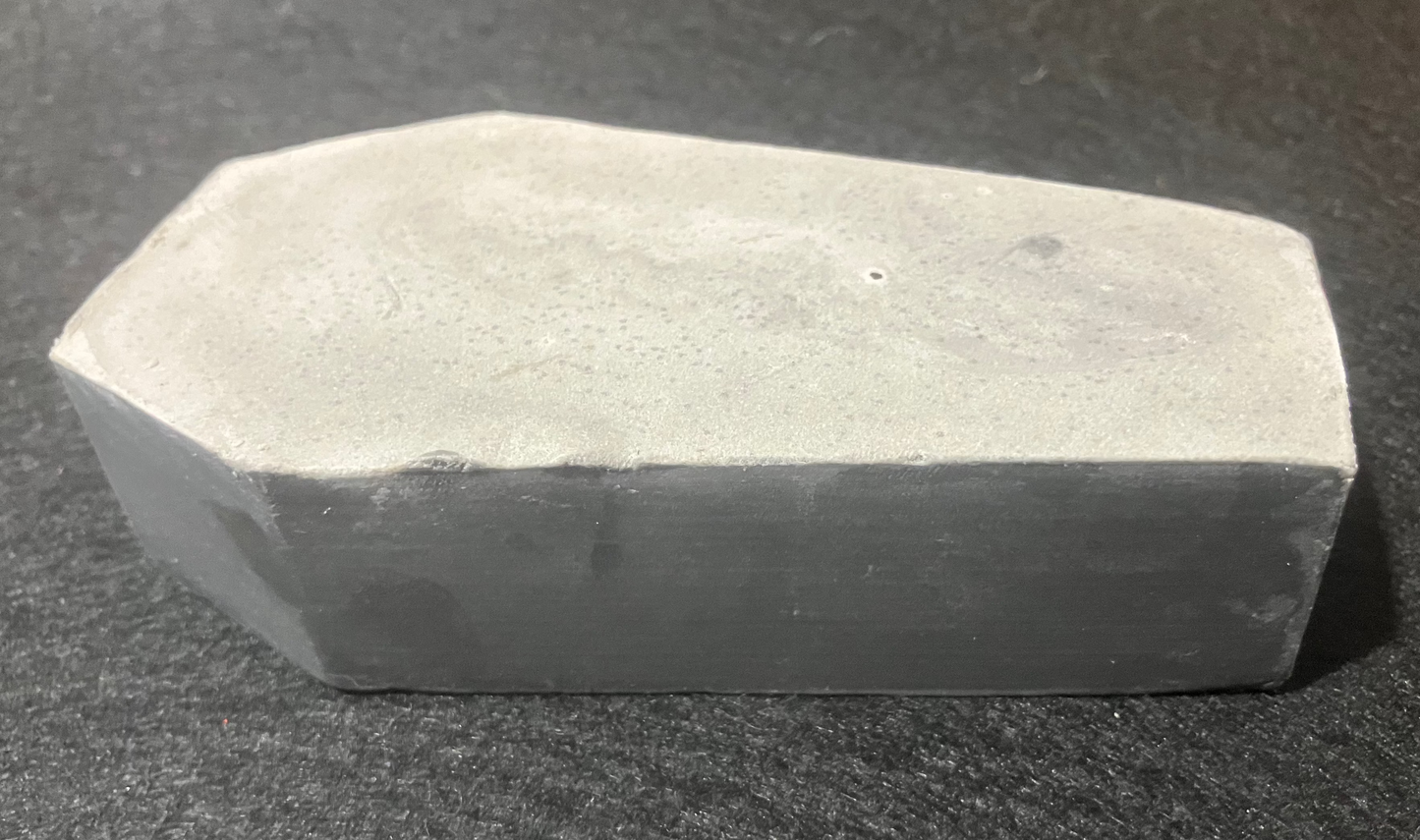Coffin-shaped bar of soap on a dark surface