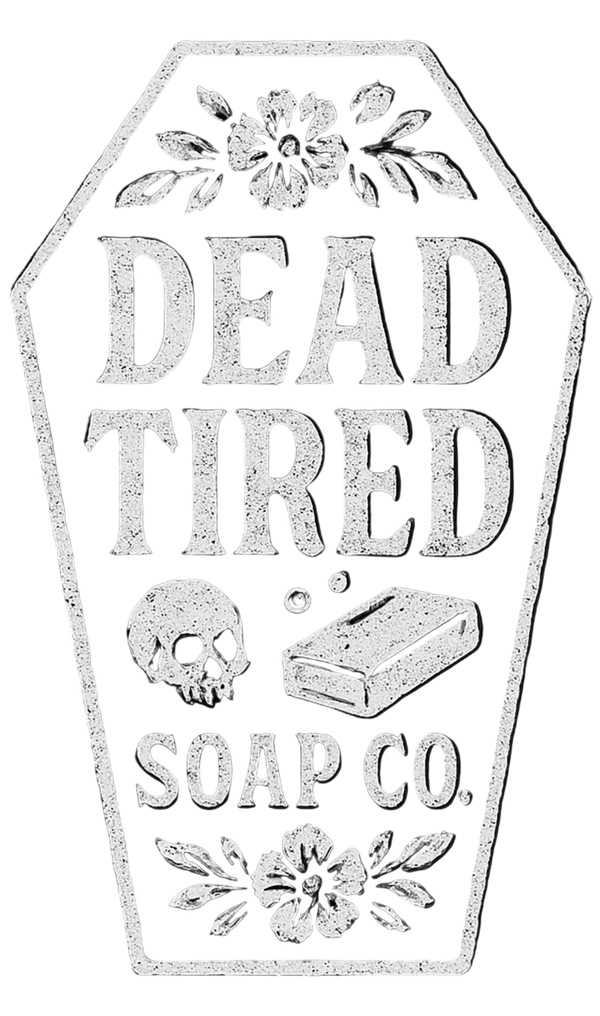 A coffin-shaped vintage-style label or sign reading 'DEAD TIRED SOAP CO.' with floral decorations at the top and bottom, plus a skull and soap bar illustration in the center, shown on a plain white background.